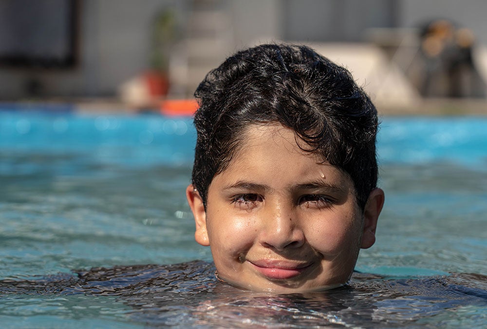 juan sonrie y nada en una piscina