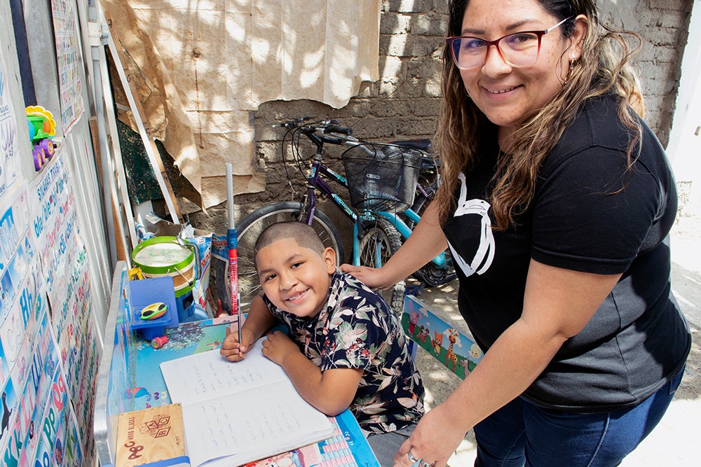 ramses and his mother rosa smiling while he does homework