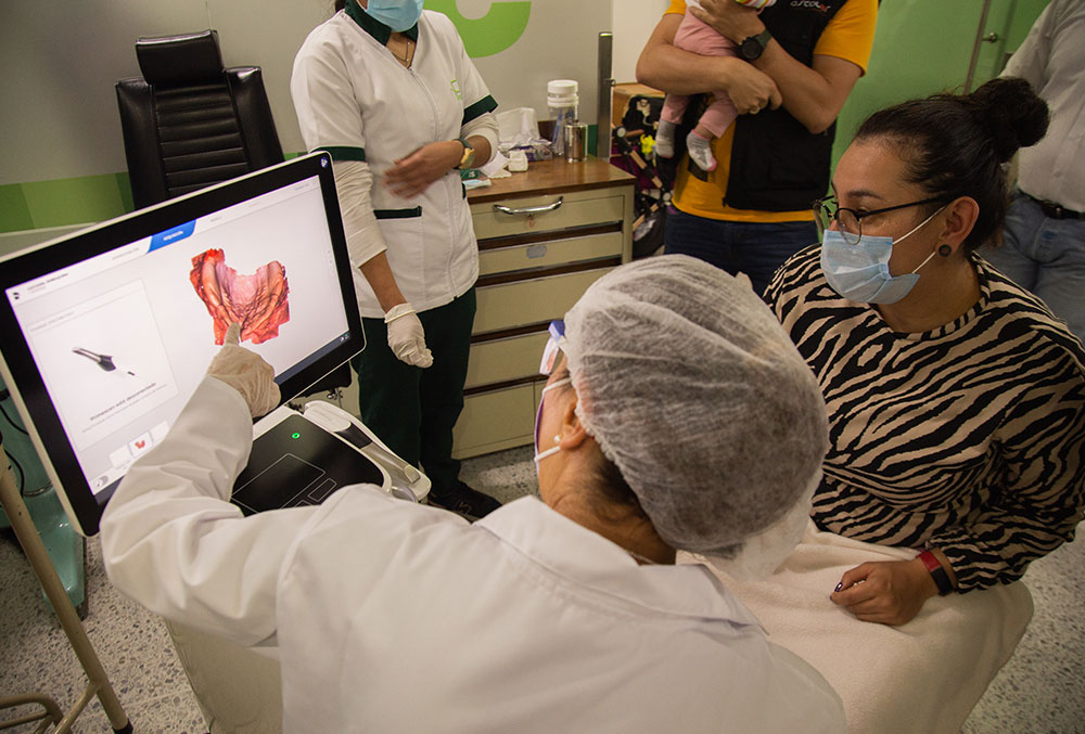 Un técnico de FISULAB revisa un escaneo 3D del Primescan AC con la madre de un paciente
