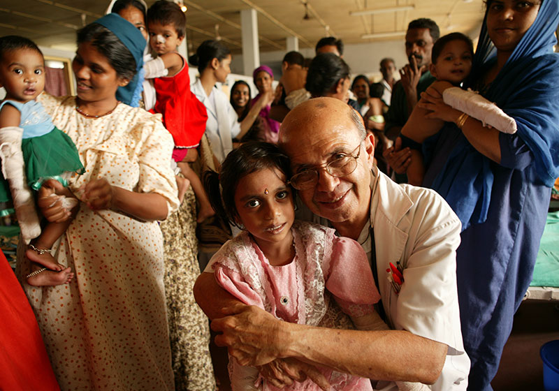 El Dr. Adenwalla sonríe y abraza a un paciente