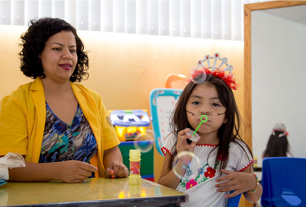 Barbara blows bubbles during a speech therapy session