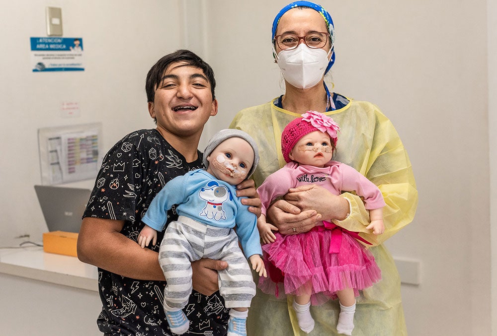 Vicente sonríe y sostiene un muñeco de simulación de Smile Train