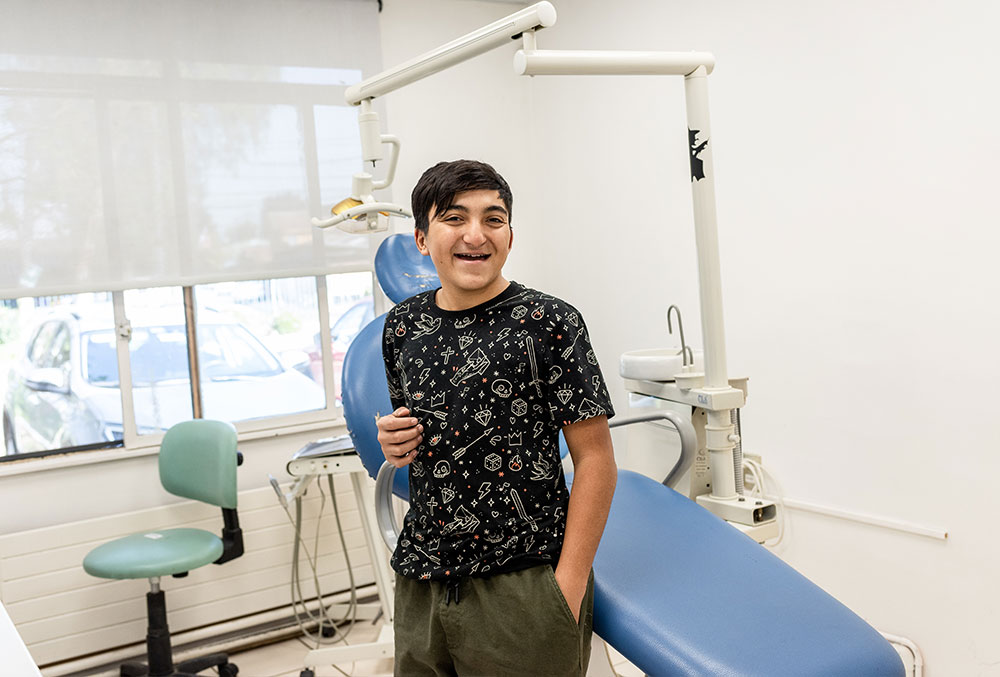 Vicente smiling in front of a dentists' chair