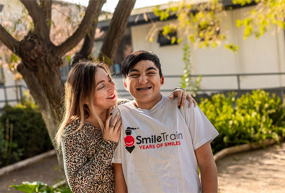 Vicente sonríe con su madre con una camiseta de Smile Train puesta