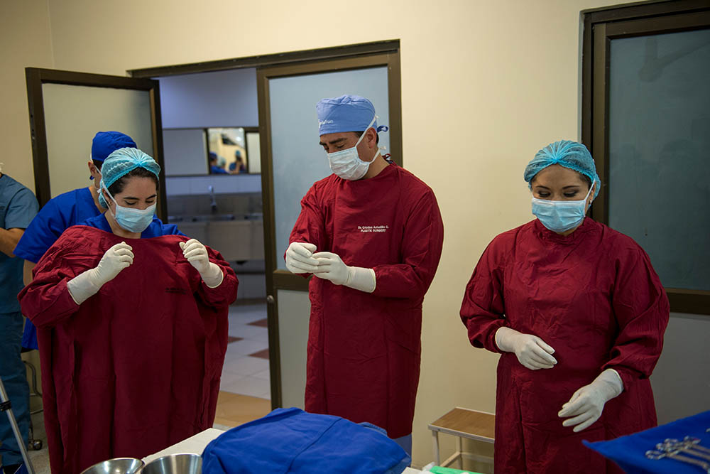 La Dra. Andrea Astudillo se prepara para la cirugía en bata roja