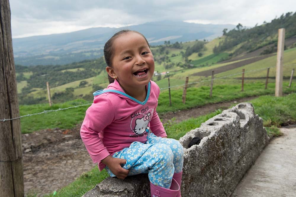 Fernanda smiling and sitting on a fence