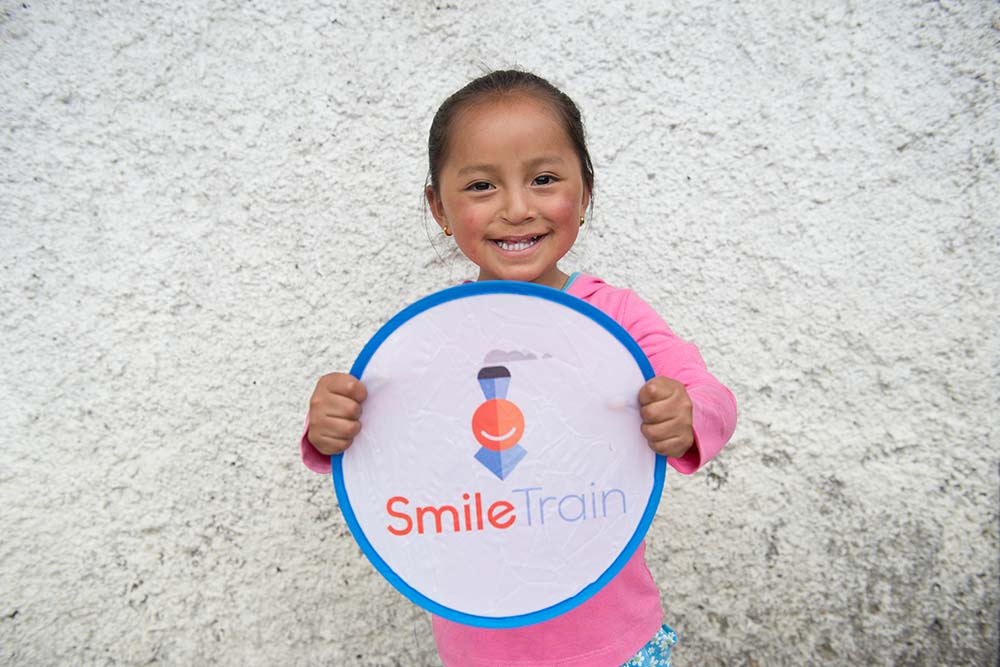 Fernanda sonríe con un cartel de Smile Train