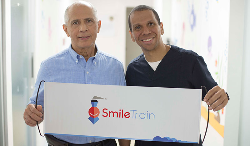 Dr. Julio Gonzalez y Dr. Carlos Alvarado sonriendo y sostieniendo un cartel Smile Train