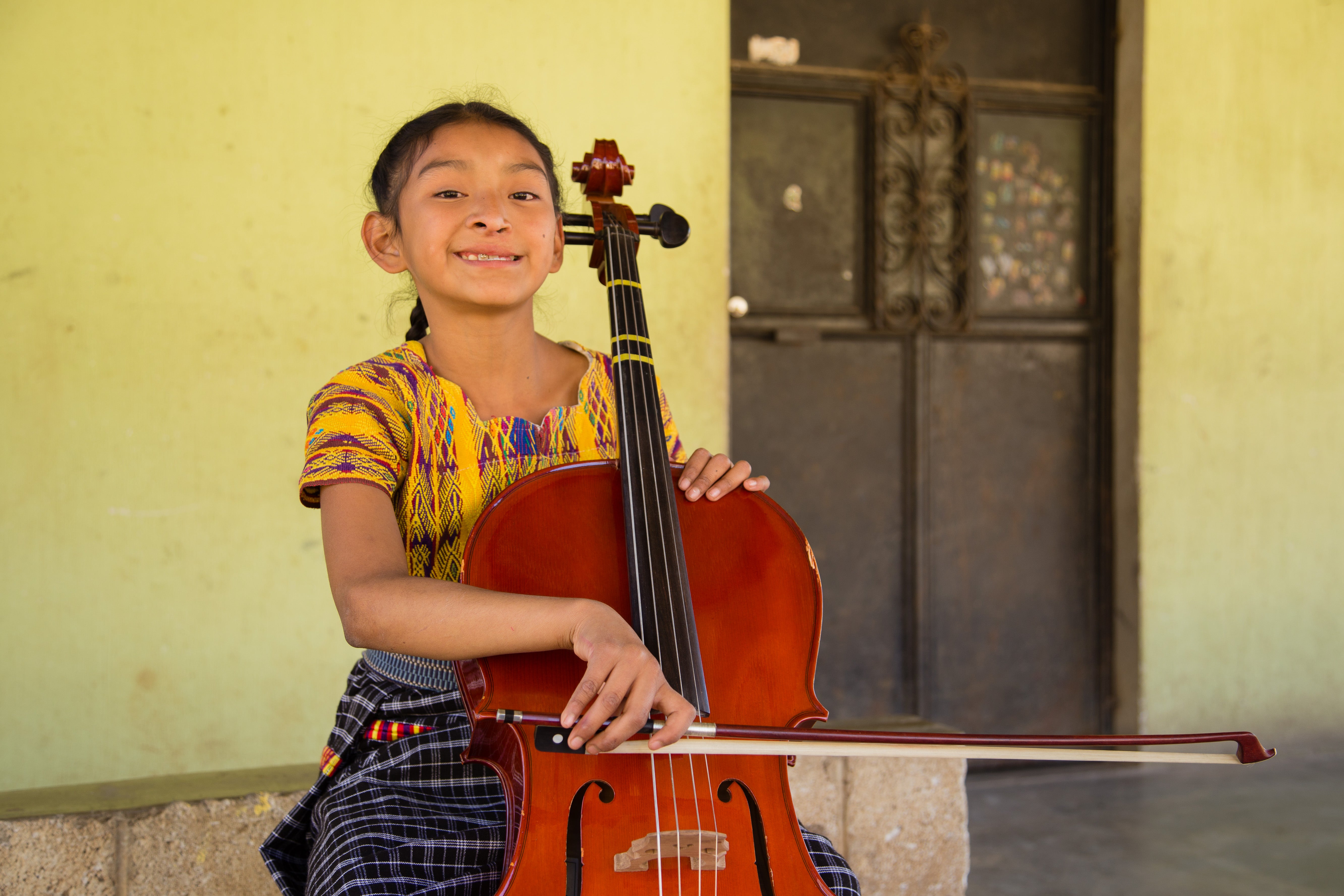 Valery sonriendo y tocando el violonchelo después de una cirugía de paladar hendido