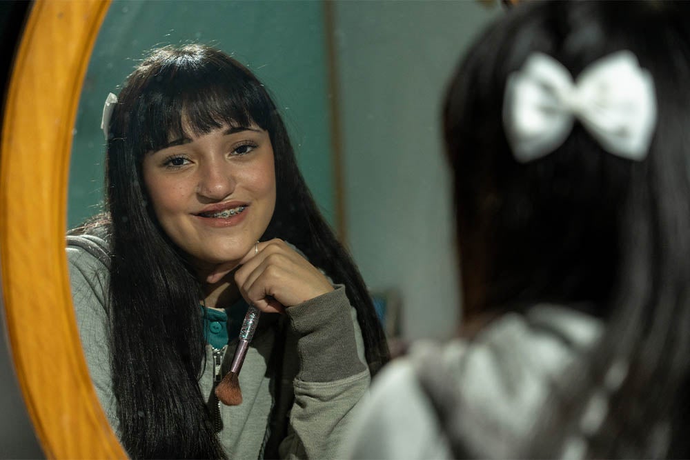 Camila looking in the mirror, putting on makeup