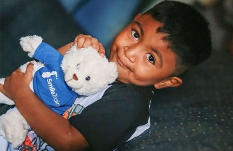 mathias smiling and holding his smile train teddy bear