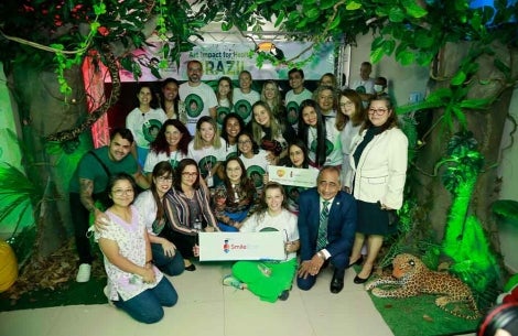 Art Impact for Health Brazil staff and partners smiling and holding Smile Train signs