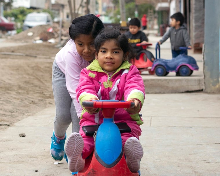 Mia anda en bicicleta con su hermana empujando