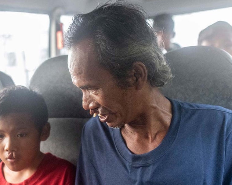 Alim sonriendo y sentado junto a Rajib en una furgoneta