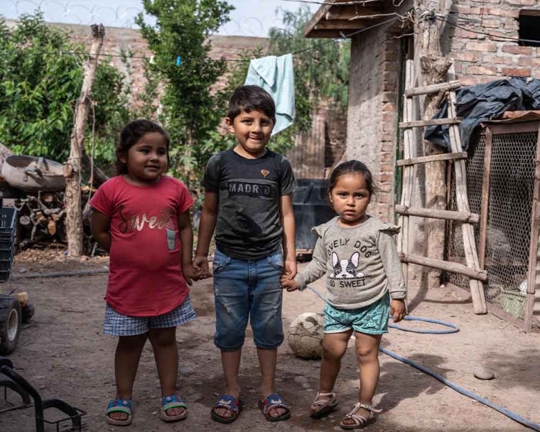 Ezequiel smiling and standing with his sisters after cleft surgery