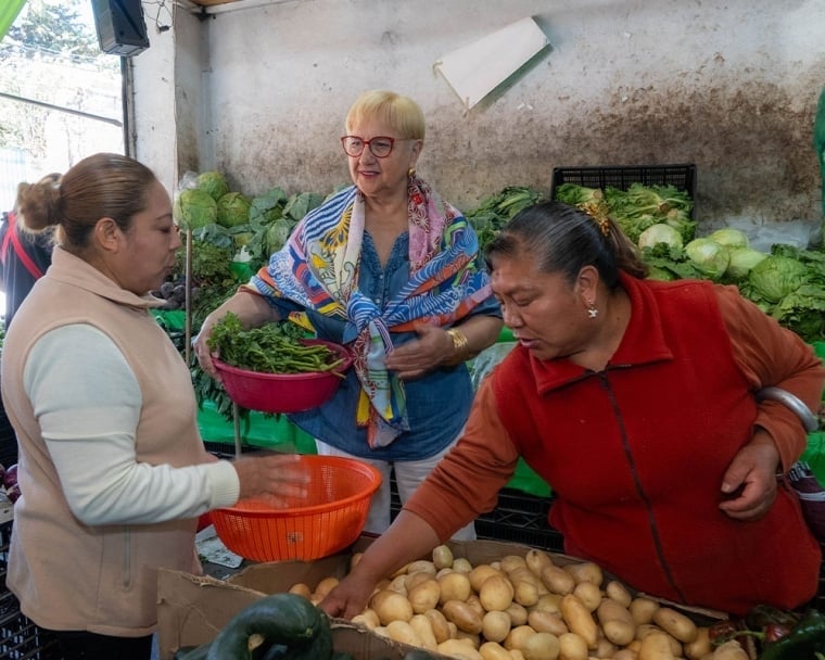 Lidia holding a basket of potatoes as another woman fills it up